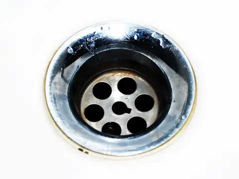 A chrome sink drain with water droplets
