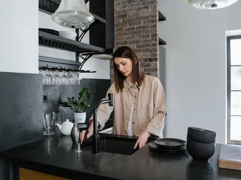 Dishes washed at a black kitchen sink by a window