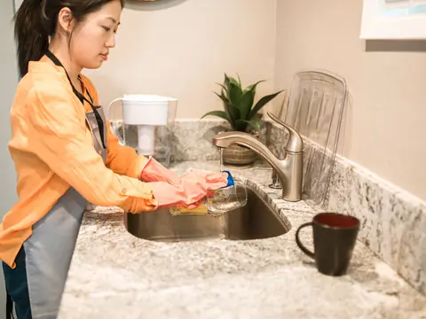 Washing up at a granite kitchen sink with a water filter pitcher on the counter