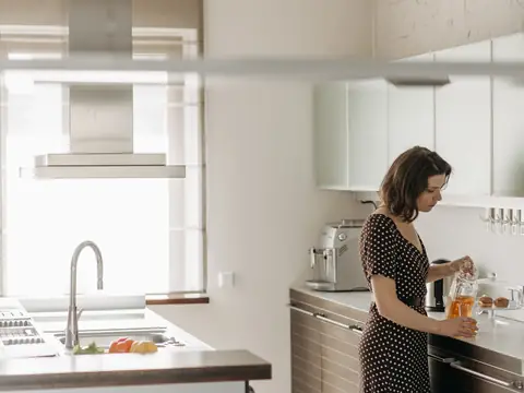A bright white kitchen with a steel sink under the window