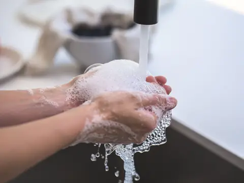 Hands rinsed under a running black tap