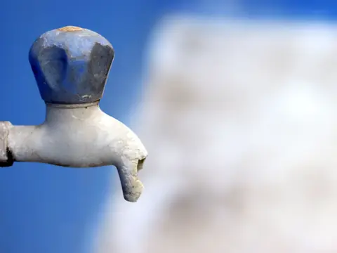 An old outdoor tap with a blue handle