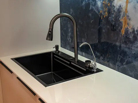 A black kitchen sink with a pull-down faucet and a separate slim drinking water tap