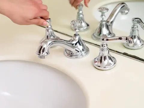 Chrome faucet handles on a cream bathroom basin