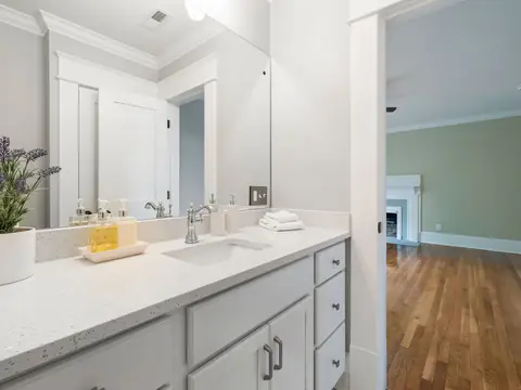A bright bathroom vanity with a chrome faucet and a vase of lavender
