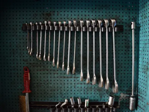 A row of wrenches hanging on a workshop pegboard
