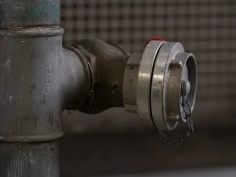 A capped fitting on a gray metal water pipe