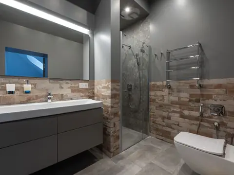 A modern bathroom with a long vanity, a glass shower and a towel warmer