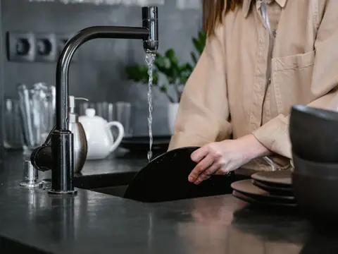 Water running from a black kitchen faucet into the sink