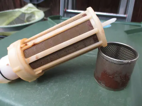 A used water filter cartridge with rust particles caught in its mesh